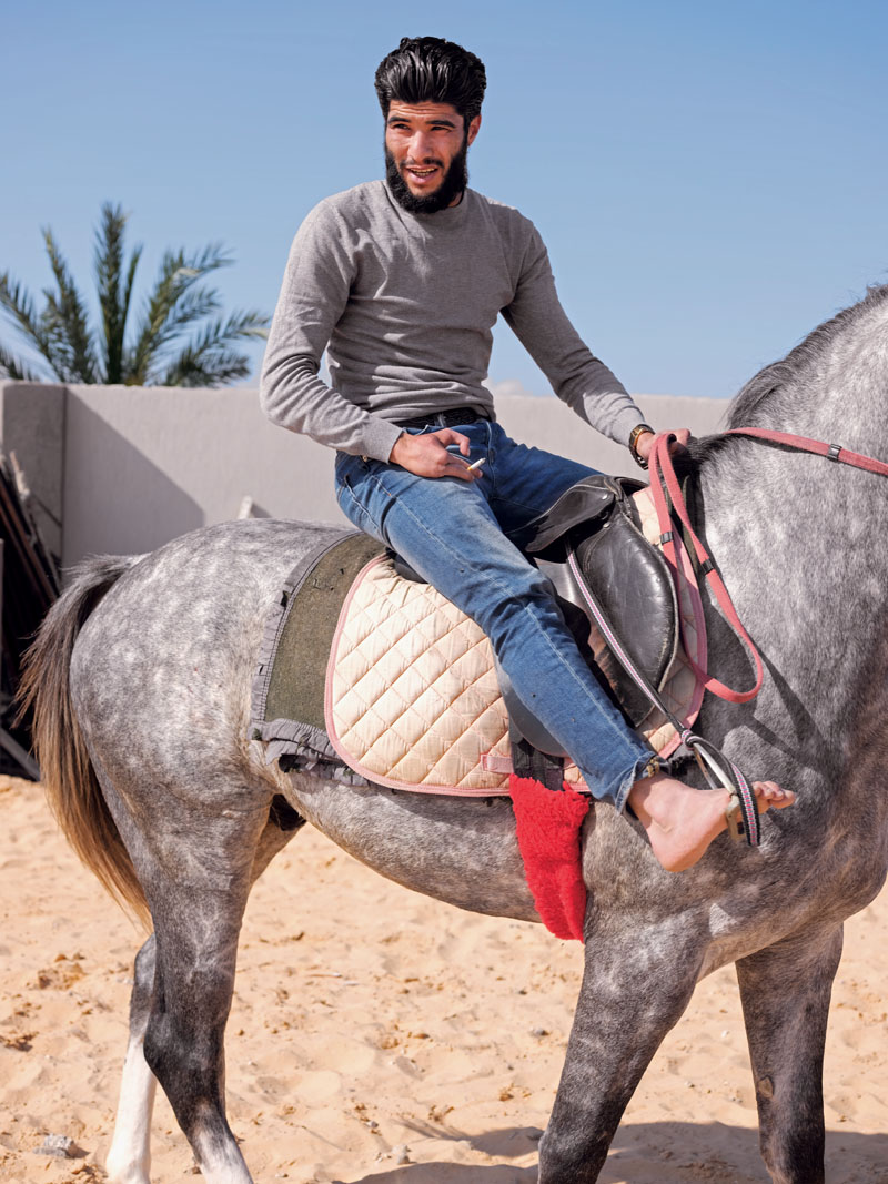 LIBYA. Zawiyah. April 5, 2017. Abdulrahman Al-Bija, a former revolutionary fighter and now a Libyan Coast Guard commander in Zawiyah, rides his horse in a farm on the outskirts of Zawiyah.