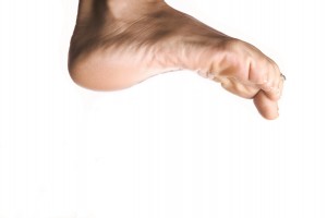 A woman getting her foot tickled by a man with a blue feather.