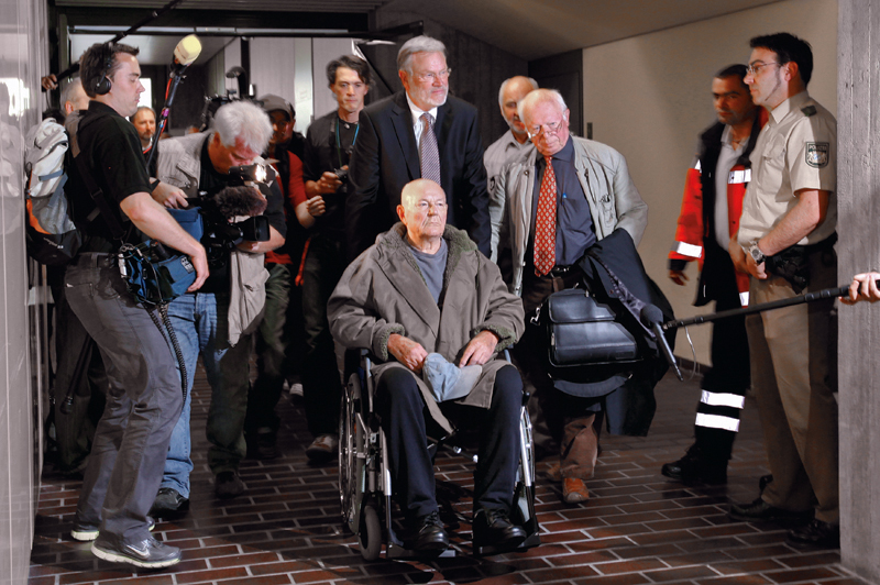 Convicted Nazi death camp guard John Demjanjuk leaves a courtroom after his the verdict in Munich on May 12, 2011. Convicted Nazi camp guard John Demjanjuk, 91, will be released from jail despite his five-year sentence for helping to kill 27,900 Jews at the Nazi death camp Sobibor because of his advanced age, the court said. REUTERS/Michael Dalder (GERMANY - Tags: POLITICS CRIME LAW IMAGES OF THE DAY) - RTR2MB6I