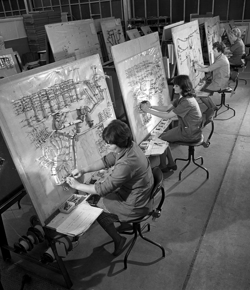 A row of women work on cable forming sections of computer at English Electric.
